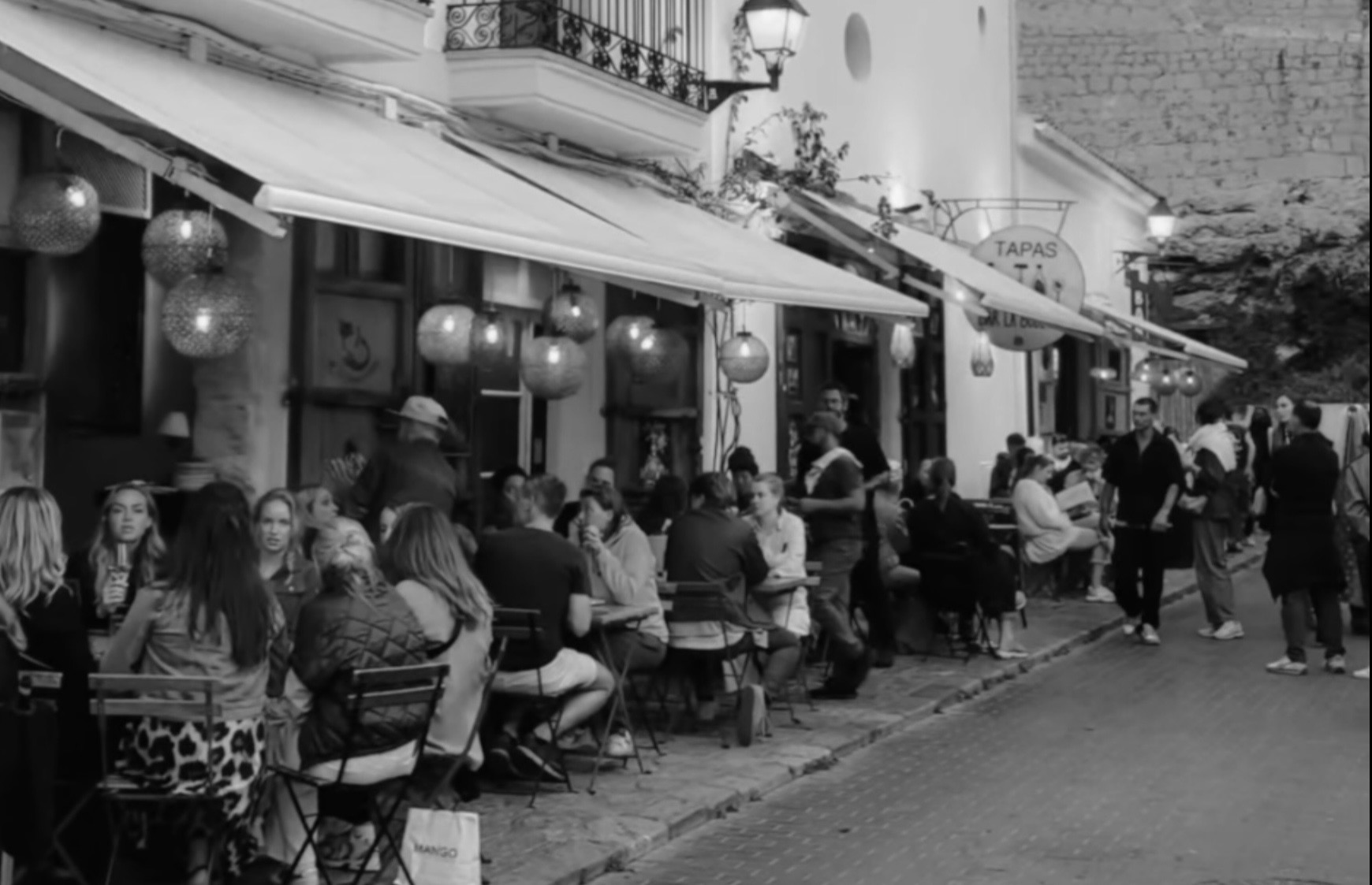 Vista de la terraza de La Bodega en sus primeros años, con clientes compartiendo mesas en una esquina histórica de Dalt Vila.