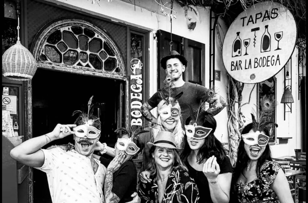 Clientes celebrando en La Bodega durante una noche festiva en Dalt Vila, rodeados de música, gastronomía y espíritu comunitario.